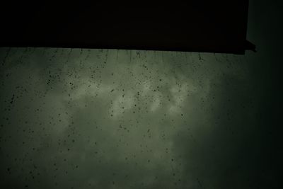Low angle view of raindrops on glass window
