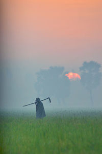 Man standing on field during sunset