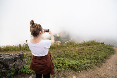 Rear view of woman photographing on mountain