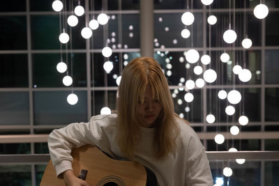 Young woman playing guitar illuminated lights
