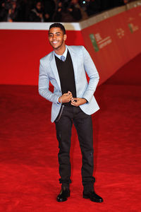 Portrait of young man standing against red wall