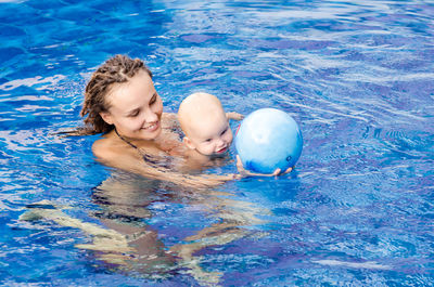 High angle view of mother with daughter swimming in pool