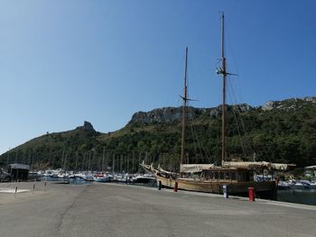 Sailboats moored at harbor against clear blue sky