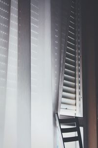 Cropped image of chair by window curtain at home