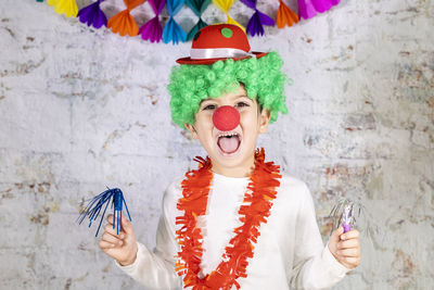 Portrait of happy boy celebrating against wall