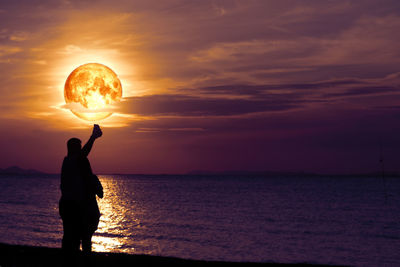 Silhouette man standing by sea against sky during sunset