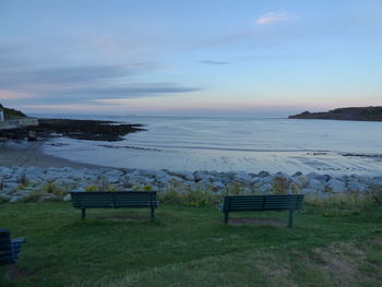 Scenic view of calm beach against cloudy sky