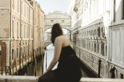 Side view of woman walking against buildings in city