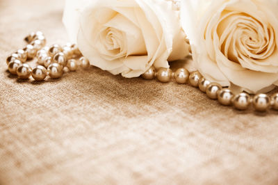 Close-up of pearl necklace with roses on table