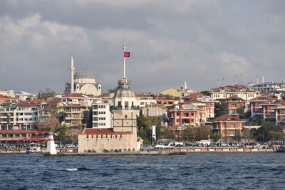 Buildings in city against cloudy sky and maiden tower