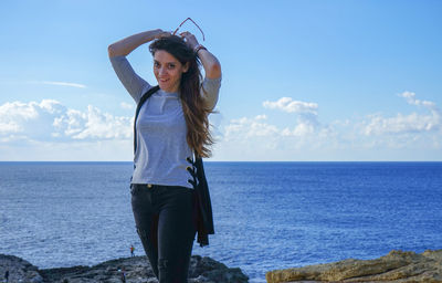 Woman standing by sea against sky