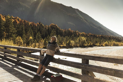 Austria, alps, woman on a hiking trip having a break on a bridge