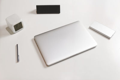 Side view of business working place with closed silver laptop, pen, clock, case for eyeglasses