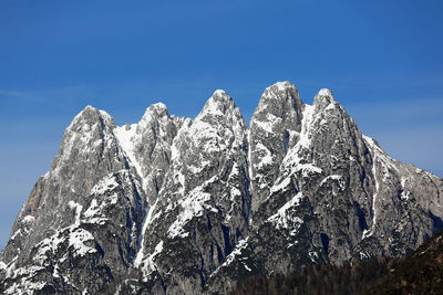 Low angle view of snowcapped mountain against blue sky