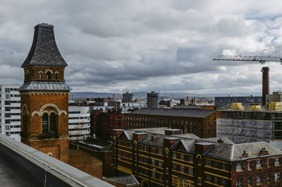 Buildings in city against cloudy sky