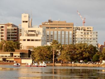 Buildings by river against sky in city