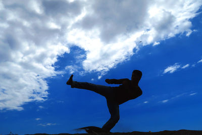 Low angle view of silhouette man climbing against sky