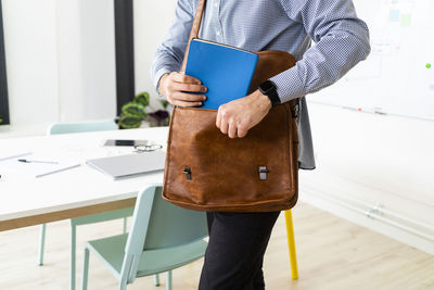 Midsection of man holding umbrella standing on table
