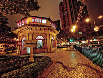 Illuminated street amidst buildings in city at night