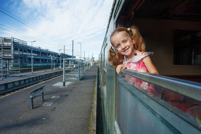Portrait of smiling young woman sitting on bridge