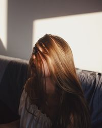 Young woman with tousled hair sitting on sofa at home