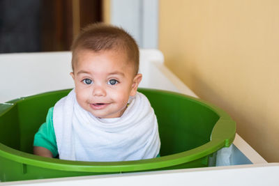 Portrait of cute baby boy in container at home