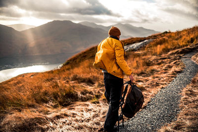 Rear view of man hiking on mountain during sunset