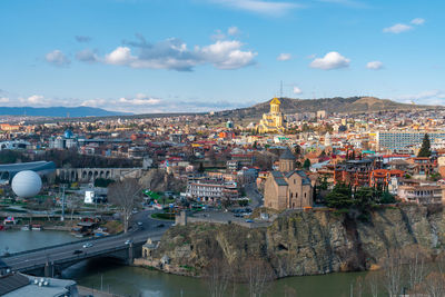 Aerial view of illuminated city by river against sky