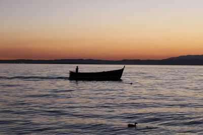 Silhouette boat sailing in sea against sky during sunset