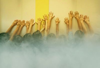 Girls with arms raised standing against wall