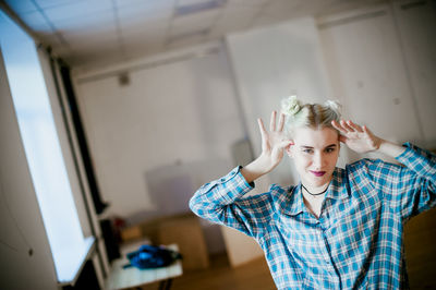 Close-up of portrait of young woman gesturing while standing at home