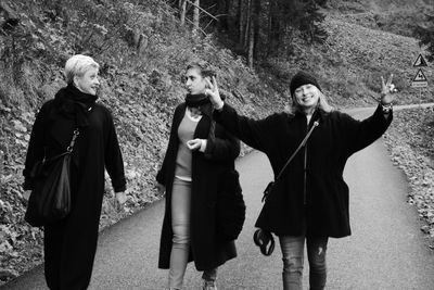 Happy female friends walking on road by mountain