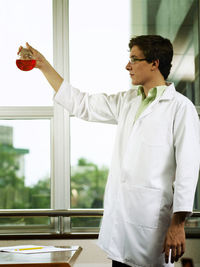 Scientist holding red chemical in laboratory glassware