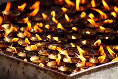 Close-up of illuminated diyas in temple