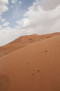 Scenic view of desert against cloudy sky