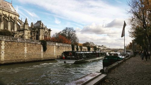 Bridge over river by buildings in city against sky