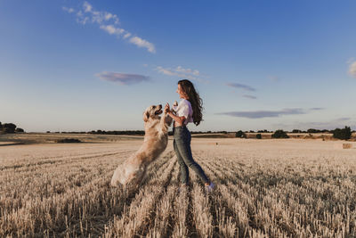 Mid adult woman with dog on agricultural field