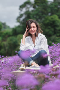 Portrait of smiling woman sitting amidst flowering plants