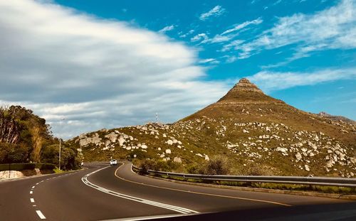 Car on road by mountain against cloudy sky