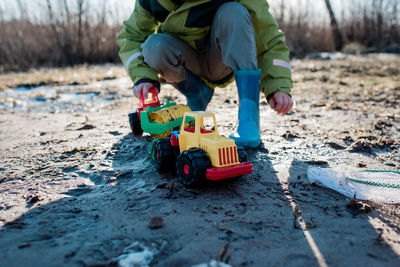 Young boy playing with trucks at the beach on his own