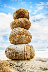 Close-up of stone stack on rock against sky 