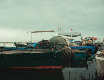 Fishing boat moored at harbor against sky