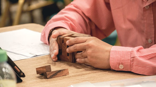 Midsection of businessman holding toy blocks on desk in office