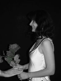 Side view of young woman against black background