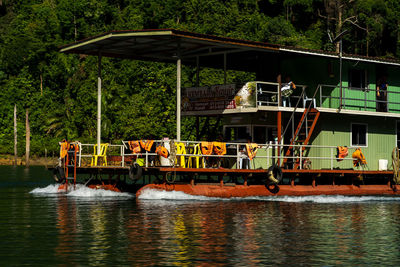 People on boat in river against trees