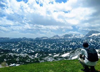 Rear view of man standing on mountain against sky