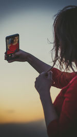 Close-up of hand holding camera against sky