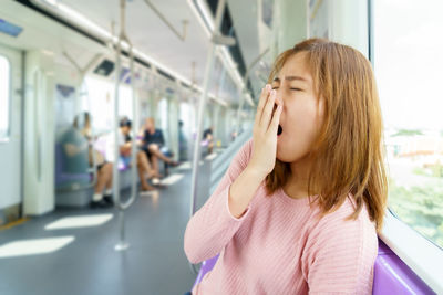 Young woman yawning in train