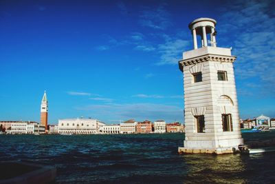 View of building by sea against blue sky