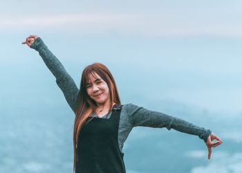 Smiling young woman standing by sea against sky